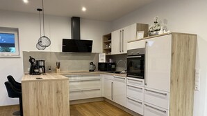 A modern kitchen with a central island, built-in appliances, and a wooden floor. - Relax in the luxury vacation home Geest & Moor 1 (Großheide)