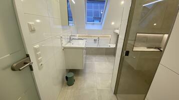 Een moderne badkamer met dakraam, grote spiegel en een ruime douche.