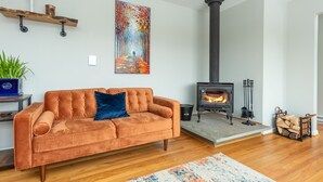 A living room with a sofa, a painting, a fireplace, and a plant. - Mountain Getaway w/ Hottub, Views, Gamesroom, Fire Pit (Roxbury)