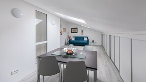 A modern dining area with a glass-top table, two chairs, a blue sofa, and a geometric wall decoration. - Maisonnette Il Todeschino B12 by Wonderful Italy (Sirmione)