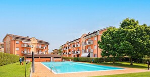 En bostadsbyggnad med en swimmingpool och en skylt som visar texten ”SMART WORKING”.
