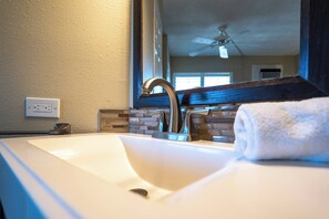 Une salle de bain avec un lavabo blanc, un miroir et une serviette.
