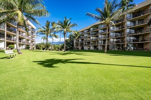 Un hôtel à étages, doté de balcons et d’une pelouse bien entretenue agrémentée de palmiers.