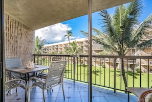 Un balcon avec une table et des chaises, donnant sur une piscine et un immeuble doté de nombreux balcons.