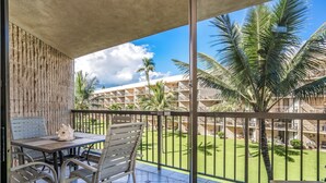 Varanda com mesa e cadeiras, vista para uma piscina e um edifício com várias varandas.