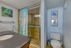 A bathroom with a shower, toilet, and sink.