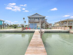 Enjoy waterfront views from the upper-level balcony of this two-story property, connected to a dock with a small platform.