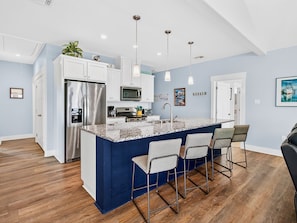 A modern kitchen with a central island, stainless steel appliances, and bar stools.