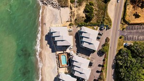 Um hotel à beira-mar com vários edifícios, uma piscina e área de estacionamento.