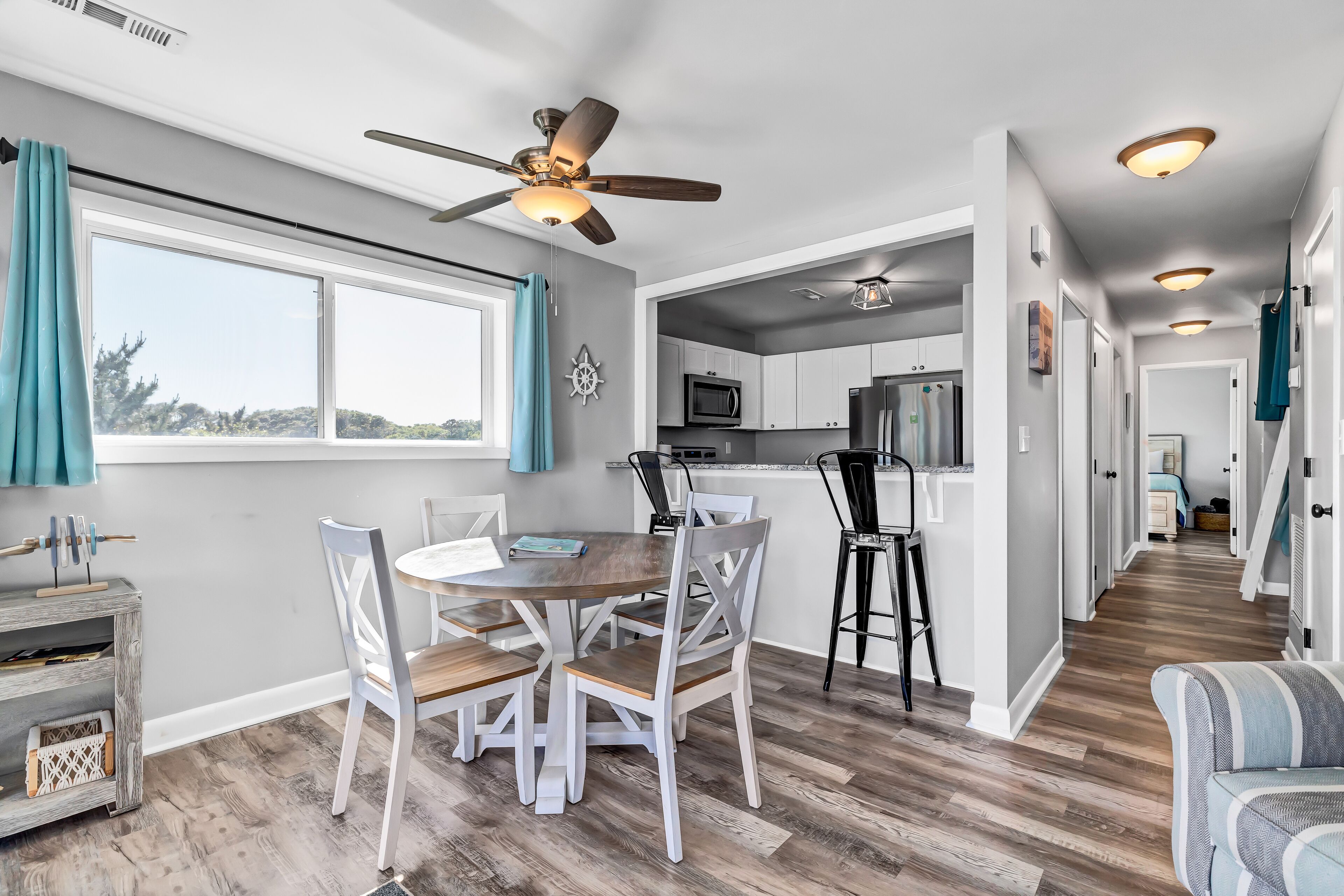 A modern kitchen with white cabinets, a microwave, and a ceiling fan.
