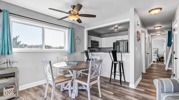 A modern kitchen with white cabinets, a microwave, and a ceiling fan.