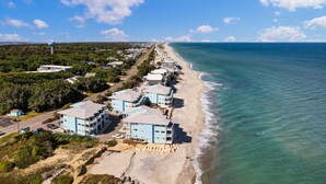 Uma propriedade costeira com villas na orla, uma praia arenosa e vista clara do oceano.