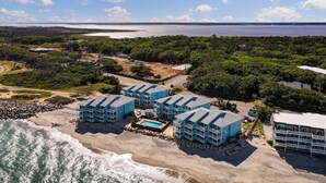 Um resort costeiro com vários edifícios azuis, uma piscina e vista para o oceano e a praia.