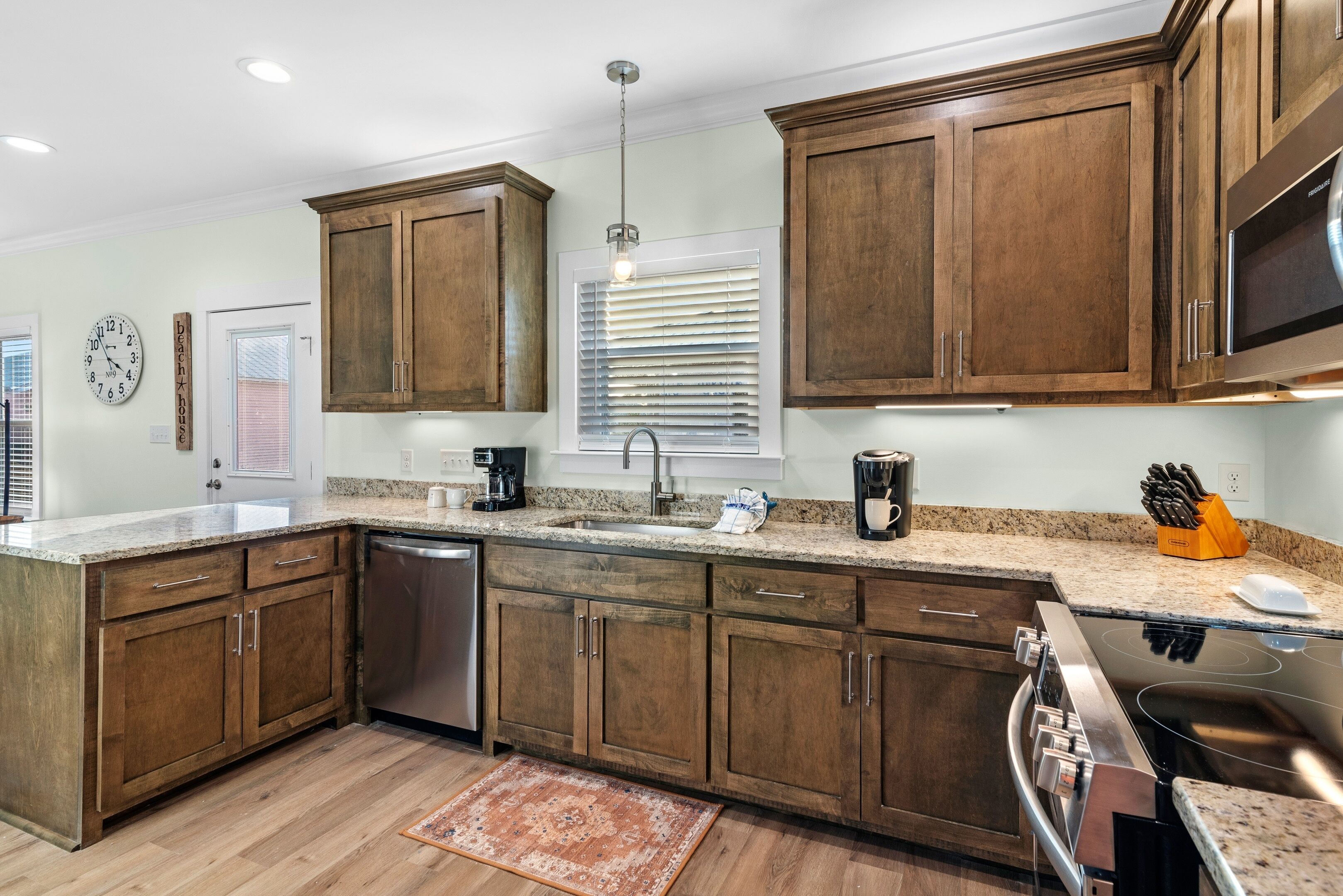 A kitchen with wooden cabinets, a stainless steel dishwasher, a built-in oven, and granite countertops.