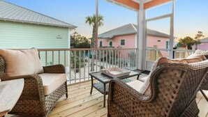 A covered outdoor area with wicker furniture, a table, and a view of neighboring houses. - The Rookery III 7022 by RedAwning (Gulf Shores)