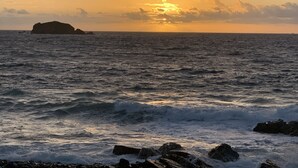 A coastal sunset with waves crashing onto rocks. - Apartment Beatitudo  (Point Blanche)