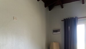 A room with a dark blue sofa against a white wall, a wooden floor, a lamp, and a window with curtains. - Apartment Beatitudo  (Point Blanche)