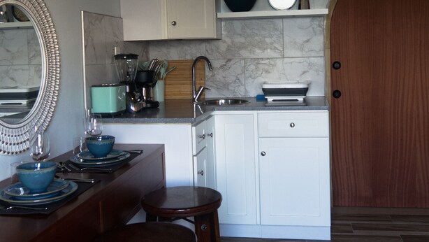 A modern kitchen with white cabinets, a marble backsplash, and a wooden door. - Apartment Beatitudo  (Point Blanche)