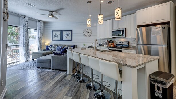 A modern kitchen with a central island, bar stools, stainless steel appliances, and pendant lighting. - Sunset Rentals | Ocean Breeze 44 | Dog Friendly (Hilton Head Island)