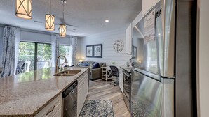 A modern kitchen with a built-in dishwasher, stainless steel refrigerator, and pendant lights. - Sunset Rentals | Ocean Breeze 44 | Dog Friendly (Hilton Head Island)