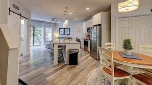 A modern kitchen with a central island, stainless steel appliances, and a dining area with a wooden table and chairs. - Sunset Rentals | Ocean Breeze 44 | Dog Friendly (Hilton Head Island)
