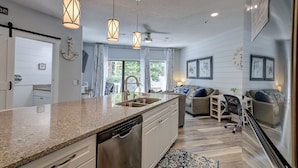 A modern kitchen with granite countertops, stainless steel appliances, and pendant lighting. - Sunset Rentals | Ocean Breeze 44 | Dog Friendly (Hilton Head Island)