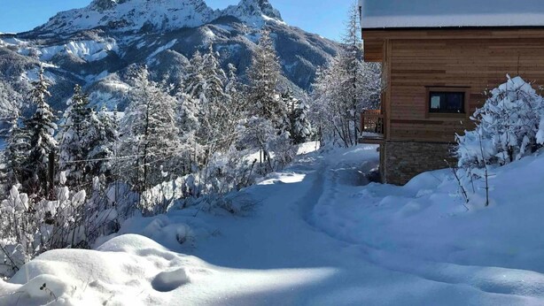 Een houten hutje met uitzicht op besneeuwde bergen.