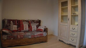Een houten bank met een lappendeken hoes en een houten kast met glazen deuren.