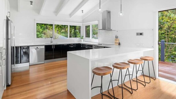 A modern kitchen with a large island, bar stools, and a view of greenery outside. - Bellarine Lake House Ocean Grove (Ocean Grove)