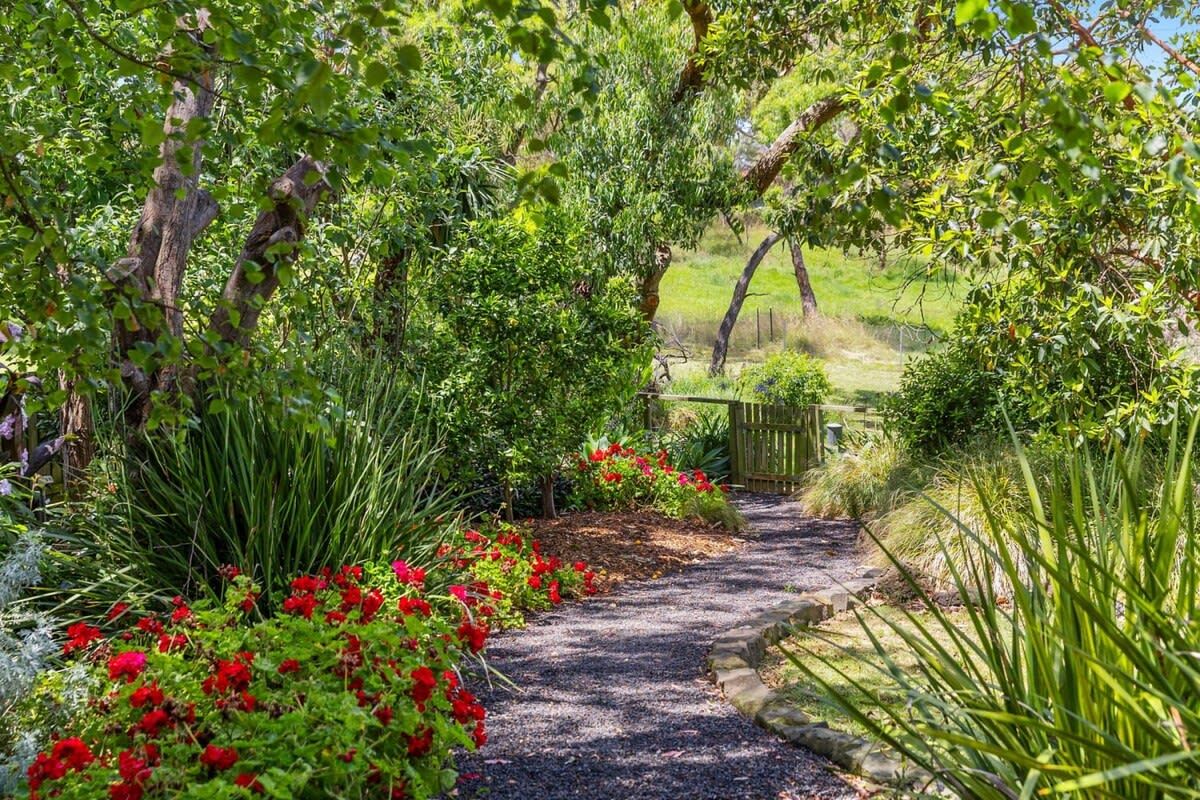 Um caminho de cascalho ladeado por vegetação exuberante e plantas floridas.