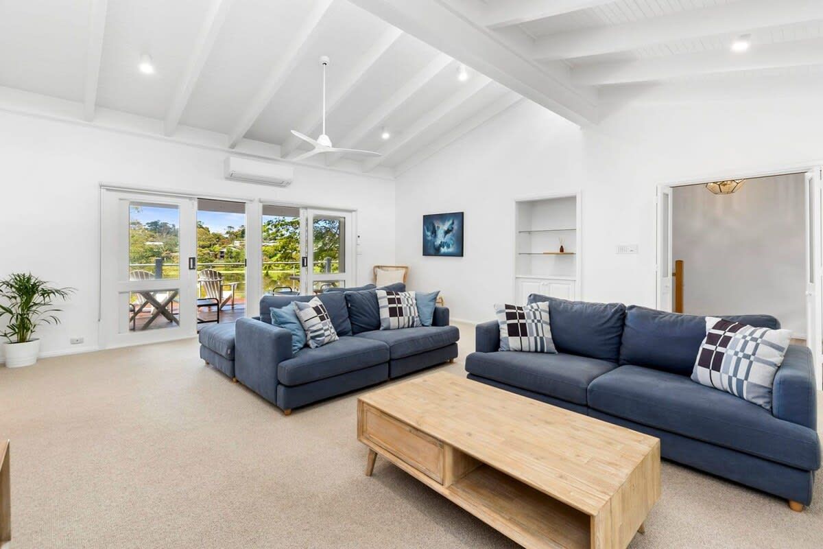 A spacious living room with a large sofa set, a wooden coffee table, and a ceiling fan.