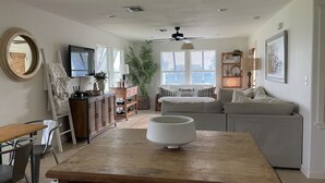 Un vaste espace de vie comprenant une table à manger en bois, un canapé et un téléviseur fixé au mur.