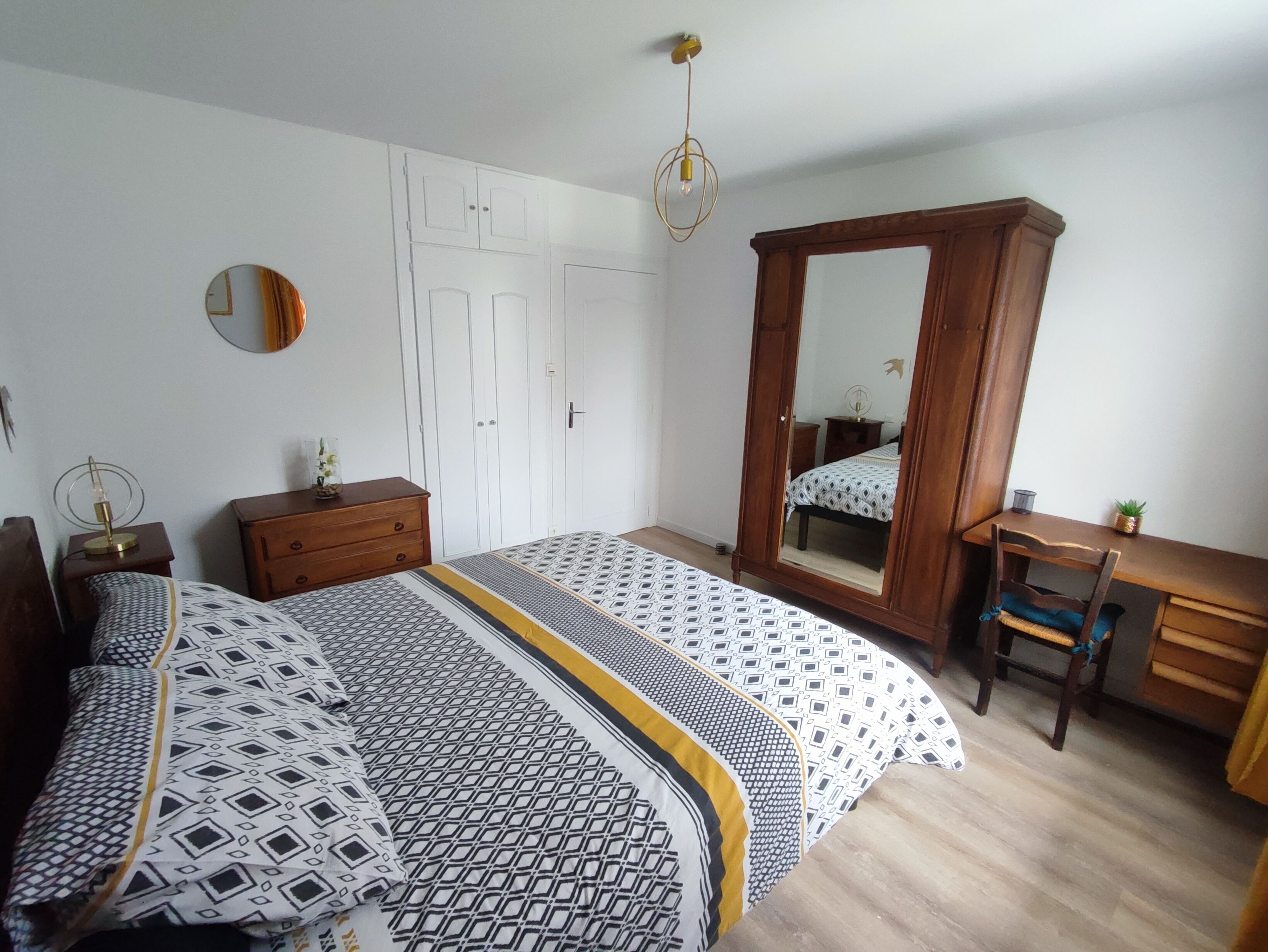 Ein Schlafzimmer mit Bett, Kleiderschrank, Schreibtisch und Spiegel.