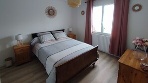 A bedroom with a wooden bed, bedside tables with lamps, a window with curtains, and wall decorations.