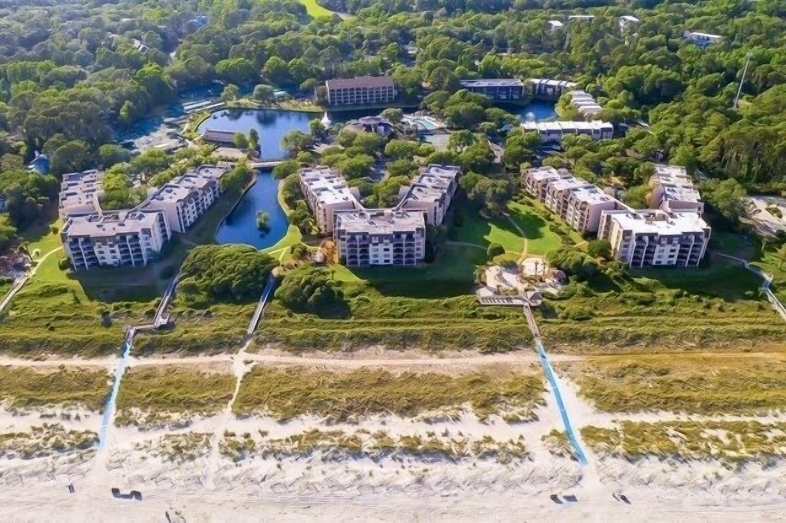 Ein Luftbild eines Resorts mit mehreren Gebäuden, die um ein zentrales Wasserelement gruppiert sind und durch Wege verbunden sind.
