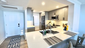 Una cocina moderna con una isla central, electrodomésticos de acero inoxidable y vistas al comedor.