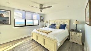 Un dormitorio con cama, mesita de noche, ventilador de techo y ventana con persianas.