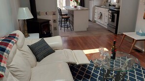 A modern living room with a sofa, a glass coffee table, and a book titled "Garden Girl". - House with Stunning Ocean View (Mulgrave)