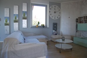 Una sala de estar moderna con un sofá, una mesita redonda y un reloj de pared grande.