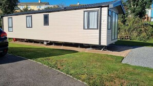 Ett hus på hjul med en enkel garageport, ett litet uthus som sitter ihop med huset och en asfalterad uppfart.
