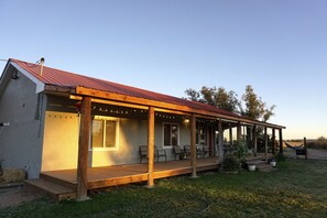 Une maison de plain-pied avec un porche abrité, un toit rouge et un petit jardin agrémenté de plantes en pot.