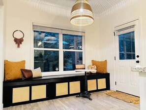 A cozy room with a built-in bench, a large window with a view, and a door with a glass panel.