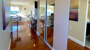 Un interior moderno con piso de madera, un área de descanso con sillas, un espejo grande y vistas a través de una ventana.