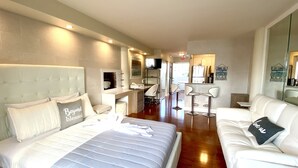 Habitación de hotel con cama, sofá, escritorio con silla, televisor y baño.