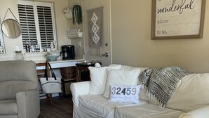 A cozy living room with a white sofa, a patterned rug, and a wooden tray table with 'Florida' written on it. - Perfectly Curated 30A Escape - Steps to Beach & Gulf Place (Santa Rosa Beach)