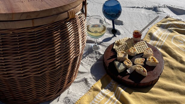 A beach setting with a wicker basket, a wooden drum, a glass of white wine, and a plate of pastries on a blanket. - Perfectly Curated 30A Escape - Steps to Beach & Gulf Place (Santa Rosa Beach)