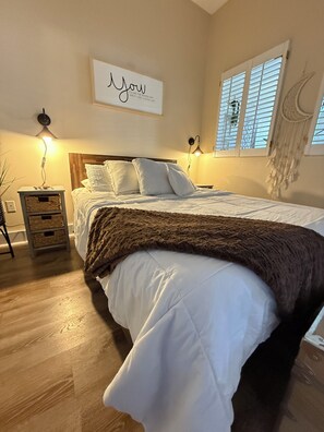 A bedroom with a bed, bedside lamps, a wall-mounted artwork, a window with blinds, and a macrame wall hanging. - You Want 30A, Stay on 30A! Salty Blonde @ Gulf Place steps from  deeded beach (Santa Rosa Beach)