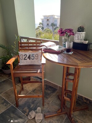 A wooden chair with a sign reading "32459 Santa Rosa Beach, FL" on a balcony with a view of a building and palm trees. - You Want 30A, Stay on 30A! Salty Blonde @ Gulf Place steps from  deeded beach (Santa Rosa Beach)