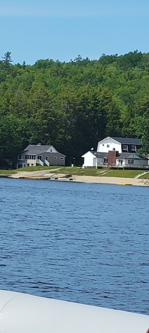 A waterfront property with houses, a dock, and a forested hill in the background.