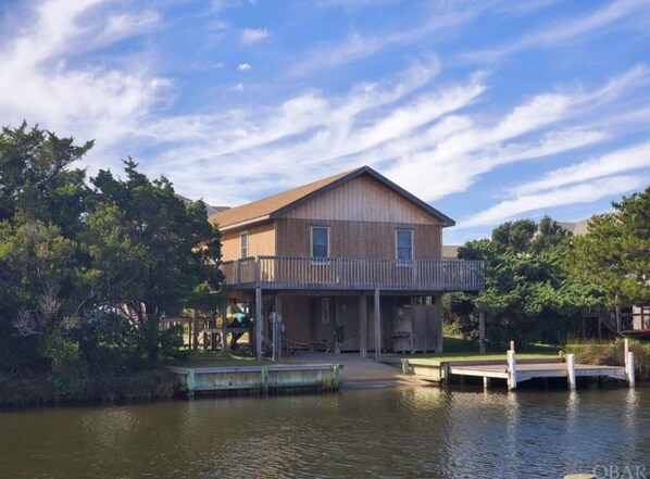 A two-story house with a balcony, situated by a body of water, surrounded by trees. - Waterfront, Dog friendly, & private boat ramp (Frisco)